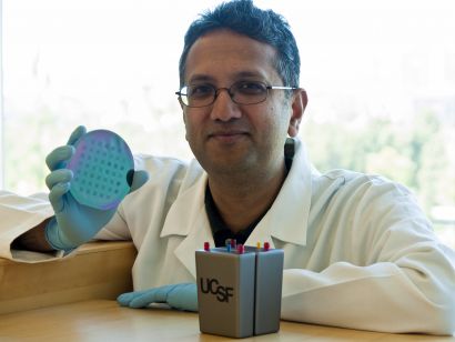 Shuvo Roy holds a silicon filter wafer next to a prototype of the artificial kidney