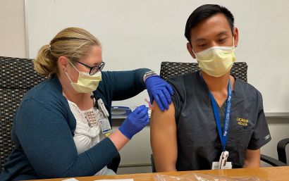 A pharmacist gives a practice vaccination to another pharmacist