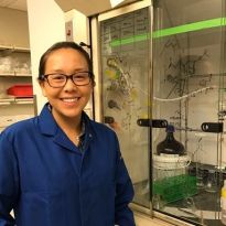 Tsai wearing a laboratory coat and standing next to laboratory equipment