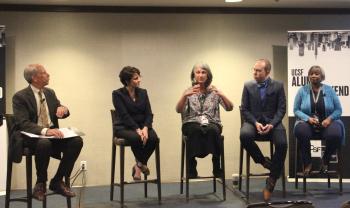 host with panel seated on stage.