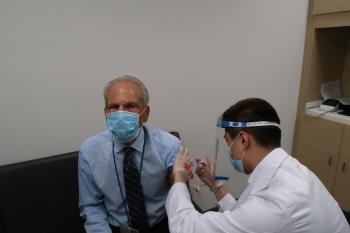 Li injects Guglielmo with the flu vaccine.