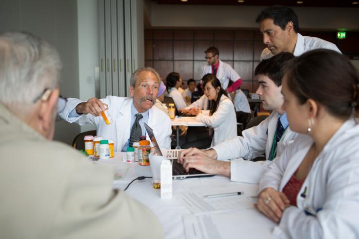 Guglielmo holding a prescription bottle and speaking to a group of students